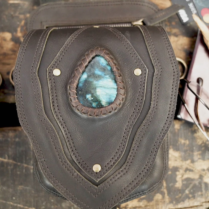 "Black leather holster harness with blue gemstone centerpiece"