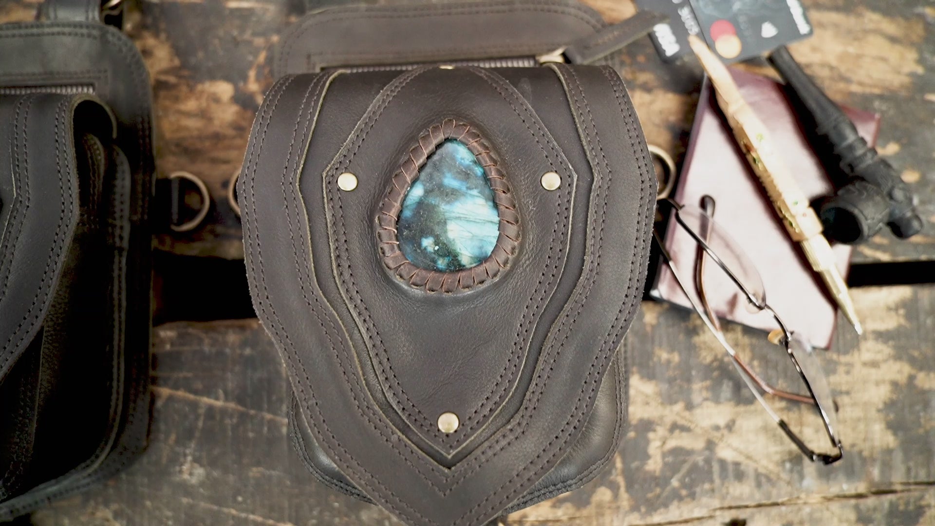"Black leather holster harness with blue gemstone centerpiece"