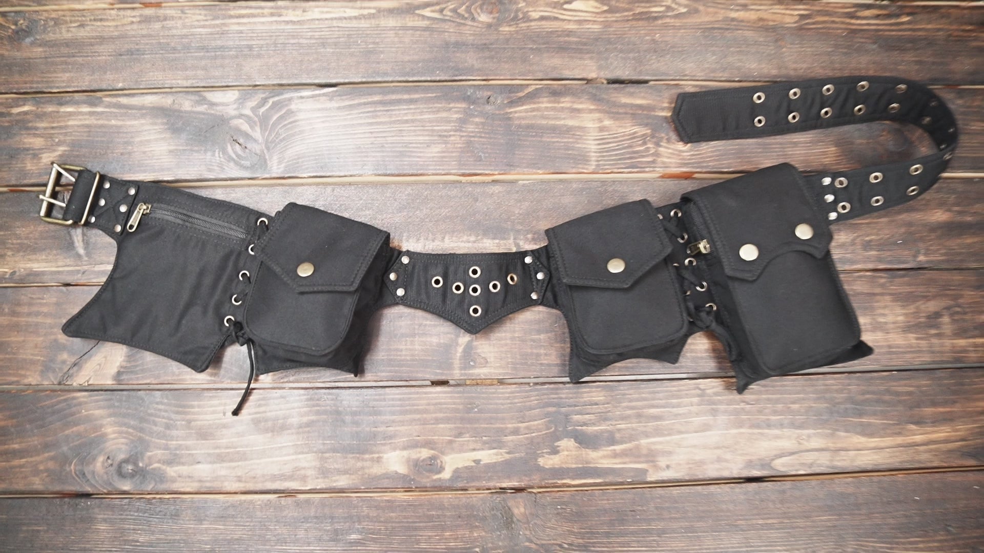 Black leather waist belt bag with multiple pockets on wooden background