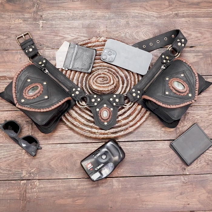 Close-up of black leather belt bag with oval gemstone detail and stitching