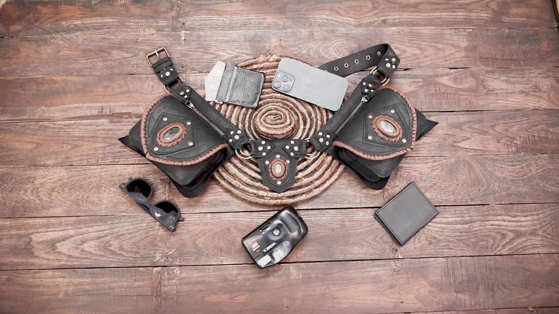 Close-up of black leather belt bag with oval gemstone detail and stitching