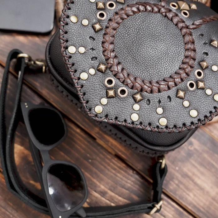 Close-up of black leather hip bag with detailed sunburst design and gold rivets