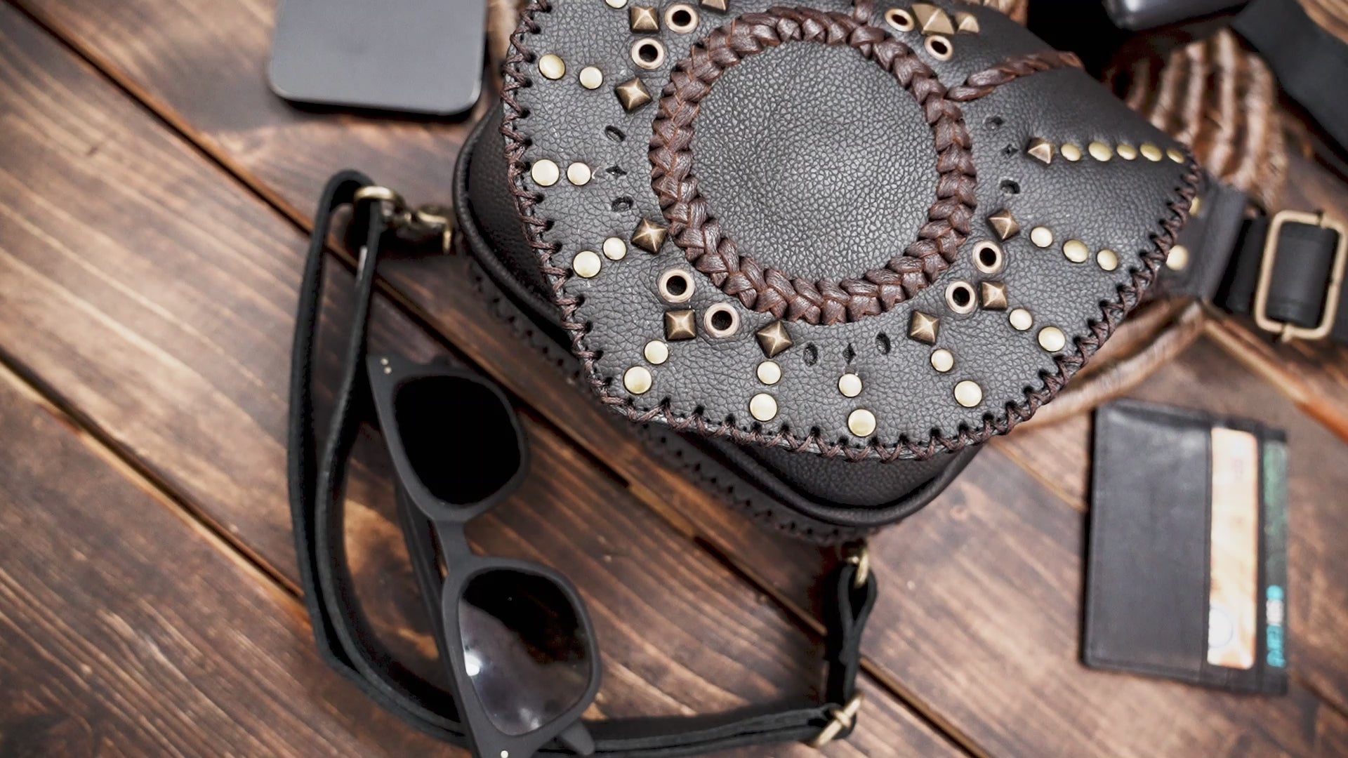 Close-up of black leather hip bag with detailed sunburst design and gold rivets